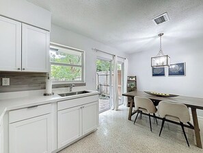 A kitchen with white cabinets, a sink, a dining table with chairs, and a chandelier. - Quiet 2 Bedroom Home Close To Beaches, Restaurants Near Boca and Fort Lauderdale (Pompano Beach)