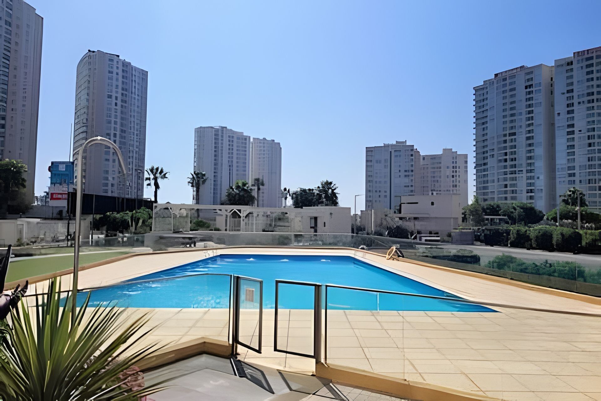 Uma piscina com deck revestido, rodeada por edifícios residenciais altos.