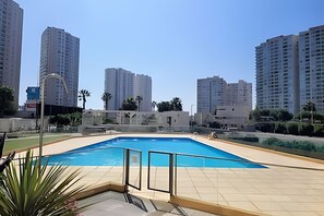 Ein Schwimmbad mit gefliestem Deck, umgeben von hohen Wohngebäuden.