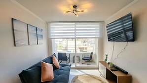 Un salon moderne avec un canapé, un téléviseur à écran plat et une grande fenêtre.
