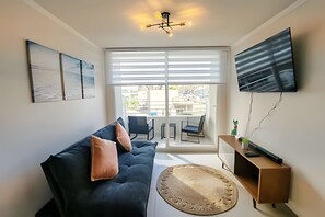Ein modernes Wohnzimmer mit einer Couch, einem Flachbildfernseher und einem großen Fenster.