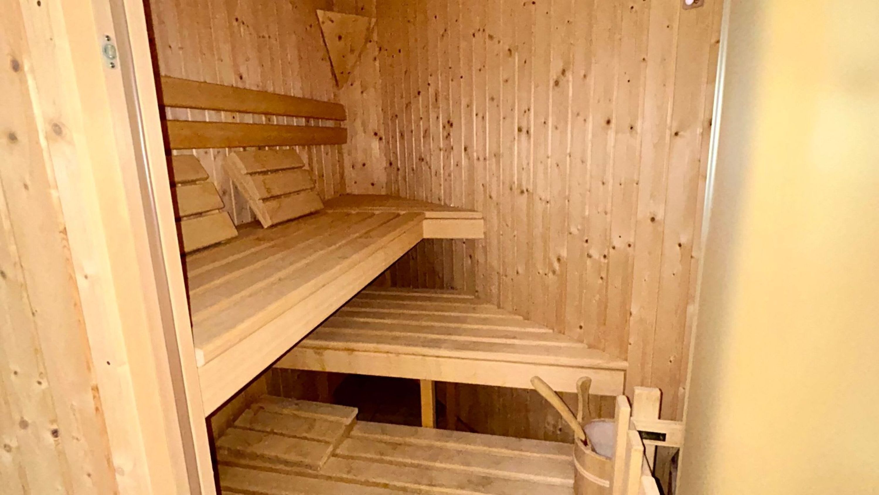 A wooden sauna with a bench and a lower platform.