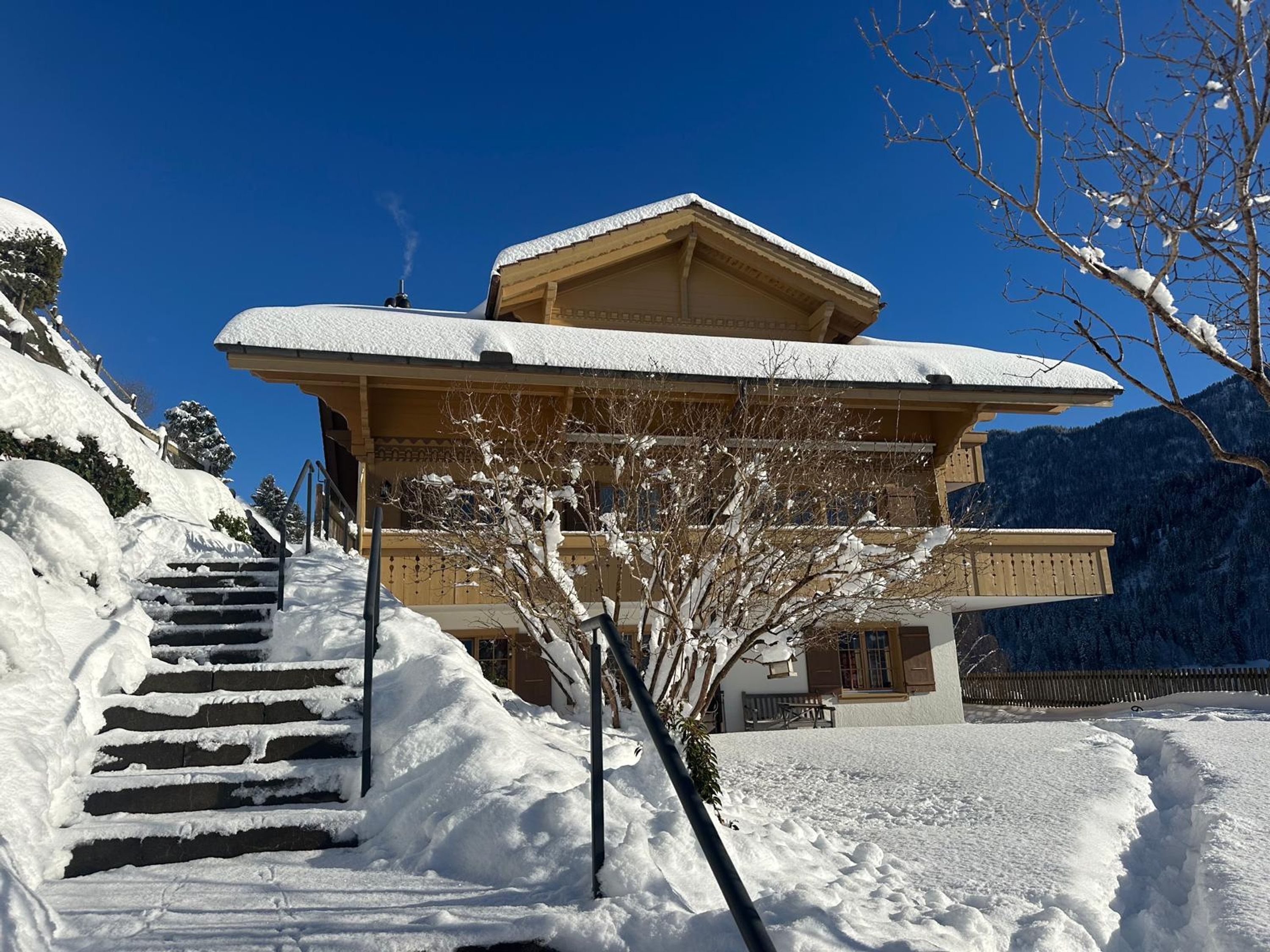 Un bâtiment à deux étages, dont le toit est recouvert de neige, et un escalier menant à l’entrée.