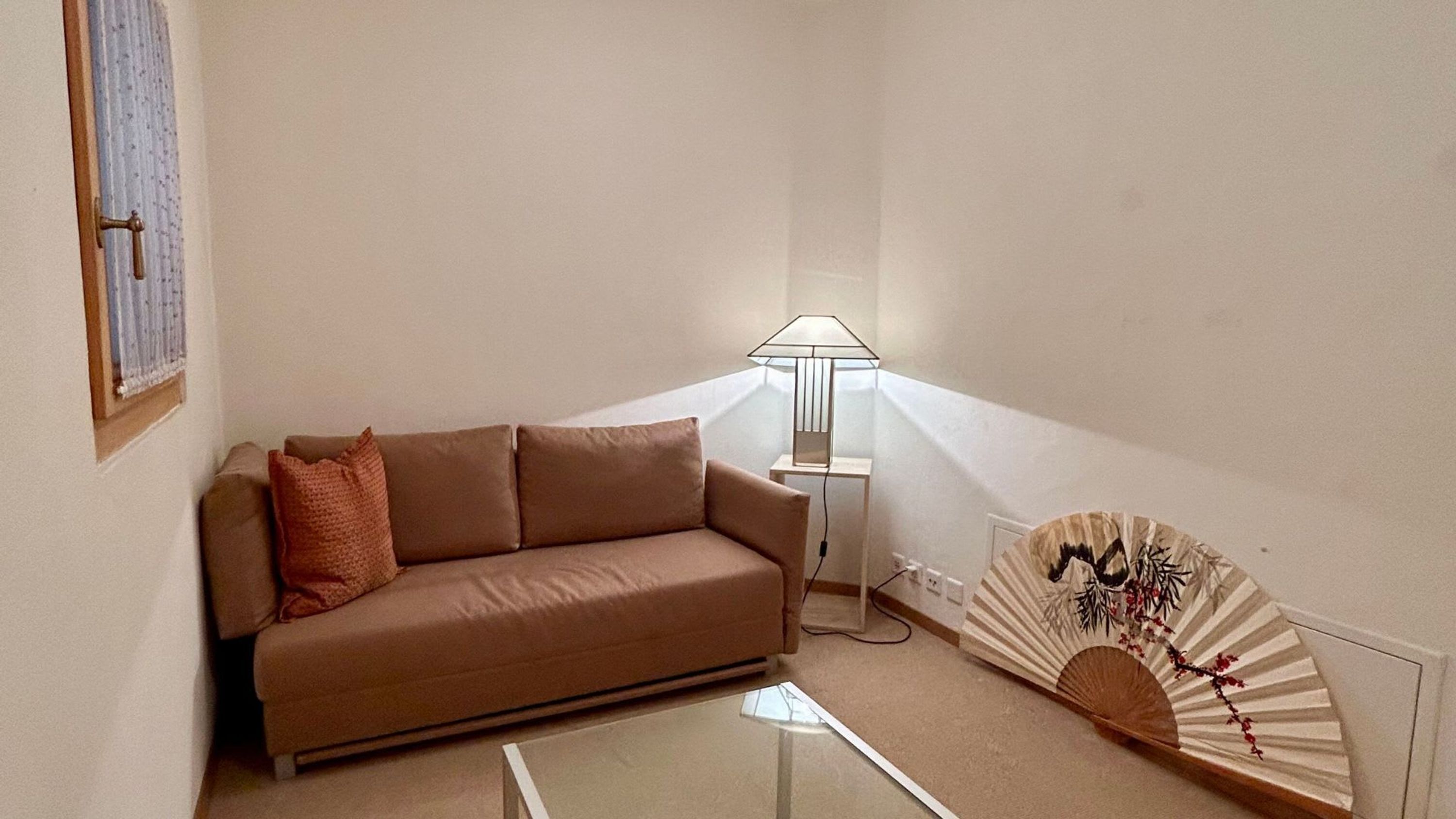 Una sala de estar con sofá, lámpara y ventilador.