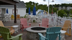 Un'area relax all'aperto con poltrone Adirondack, un braciere e un parco giochi sullo sfondo.