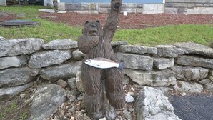 Un muro di pietra con una scultura di un orso che tiene in mano un pesce.
