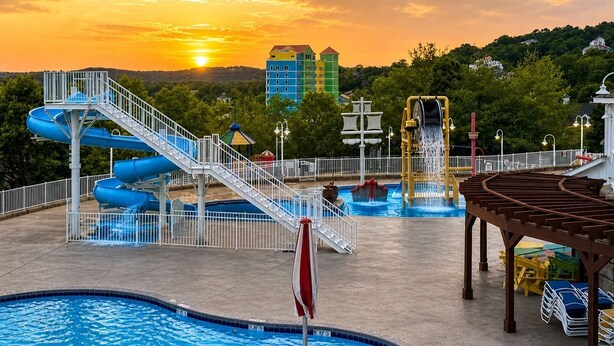 Un parco acquatico con diverse scivoli, una piscina e un tramonto sullo sfondo.