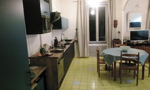 Kompakti keittiö, jossa on myös ruokailutila. Keittiöön kuuluu pesuallas, liesi sekä ruokapöytä tuoleineen.