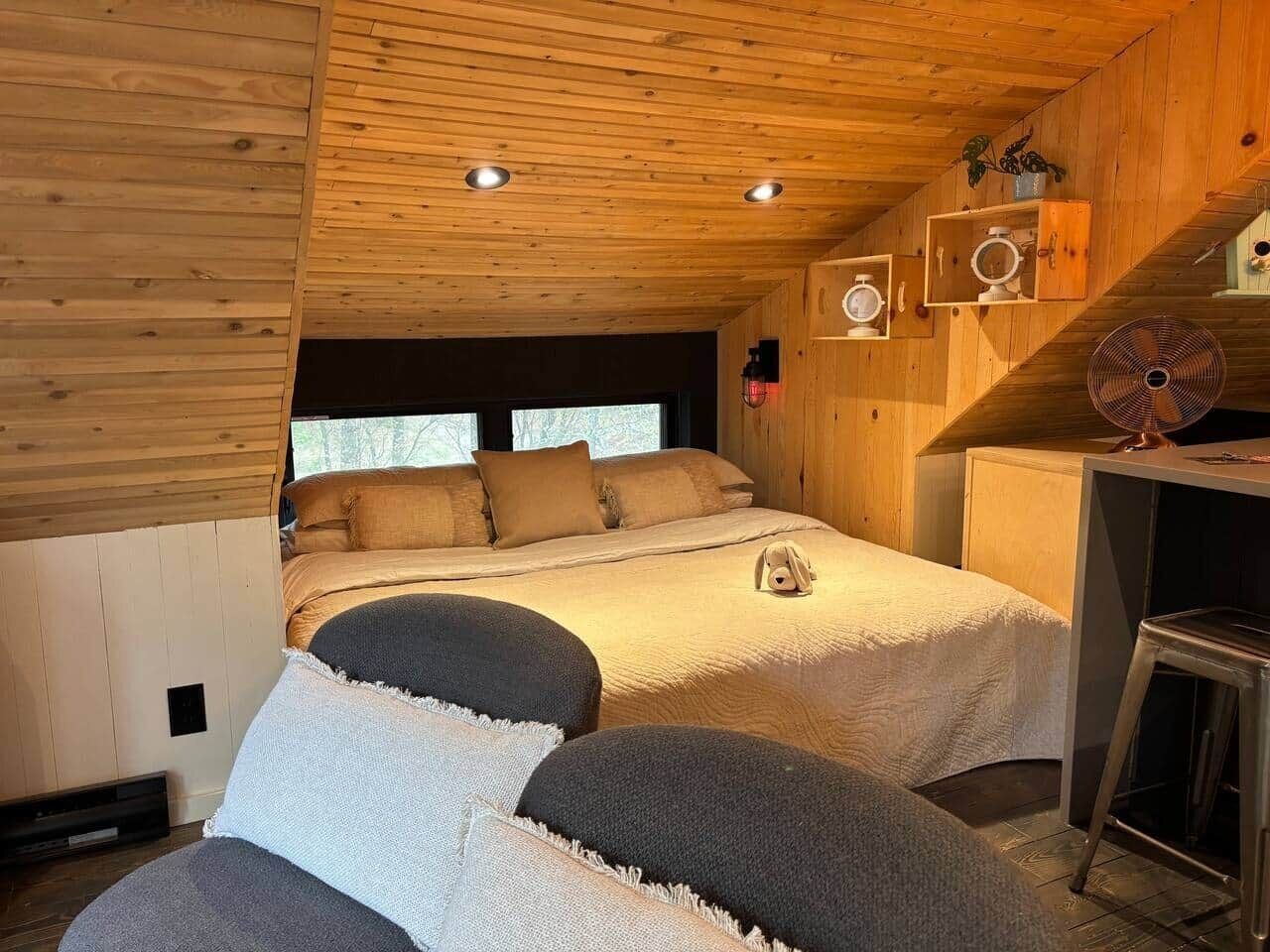 Un dormitorio acogedor de estilo cabaña, con dos camas, techo de madera y una pequeña zona de escritorio.
