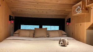 A wooden-paneled room with a bed, pillows, a stuffed toy, and wall-mounted lights. - Chalets du plateau des Hautes-Gorges : Le Grenier (Saint-Aimé-des-Lacs)