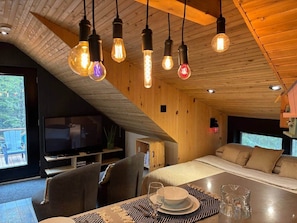 A cozy cabin interior with a dining area, a TV, and a large window.