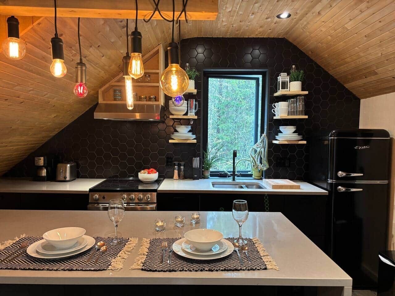 Una cocina moderna con una isla central, armarios negros y un refrigerador negro.