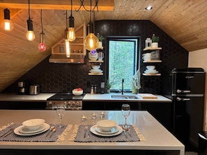 A modern kitchen with a central island, black cabinetry, and a black refrigerator.