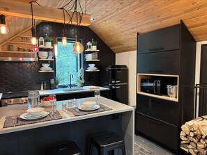 Eine moderne Küche mit einer zentralen Kochinsel, schwarzen Schränken und einer Holzbalkendecke.