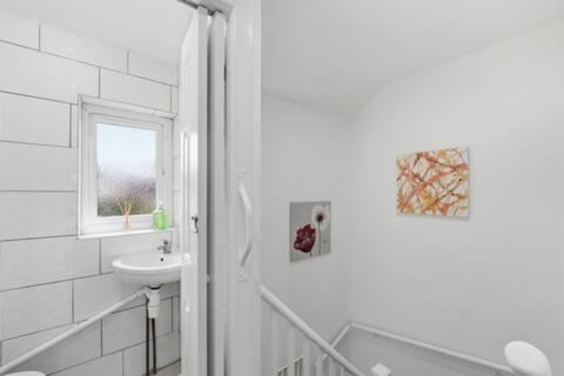 A bathroom with a white sink, a window, and a shower.