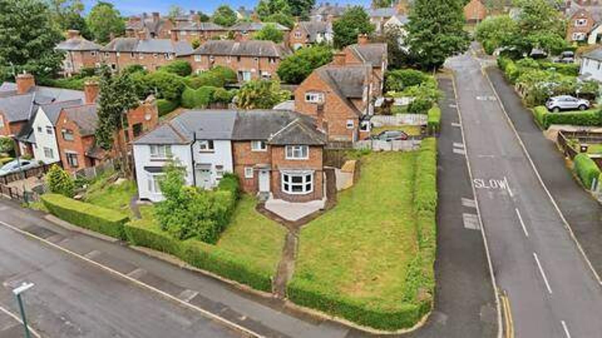 A residential street with houses, a clear road, and a 'SLOW' marking.
