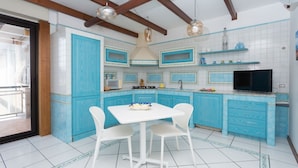 A kitchen with blue cabinets, a white table, and chairs. - Triple G Rooftop Apartment (Naples)