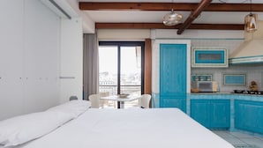 A bedroom with a bed, a small table, and a view of the city through a window. - Triple G Rooftop Apartment (Naples)