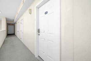 A hallway with white doors, a number sign, and a light fixture. - 🏖️Twin Palms 2204 Penthouse~Gulf-Front Views 🌅 Pool~Dedicated Parking (Panama City Beach)