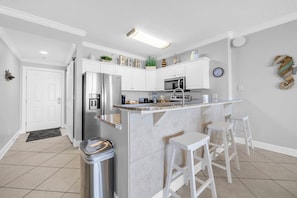 A modern kitchen with a central island, stainless steel appliances, and white cabinetry. - 🏖️Twin Palms 2204 Penthouse~Gulf-Front Views 🌅 Pool~Dedicated Parking (Panama City Beach)