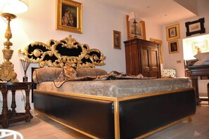 A bedroom with a large bed, ornate headboard, and a wooden wardrobe.