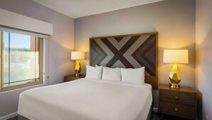 A hotel room with a large bed, two bedside tables with lamps, a geometric-patterned headboard, and a window with a view. - Delightful Resort Near Santa Catalina Mountains! (Oro Valley)