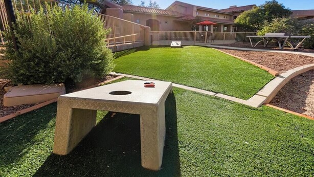 A courtyard with artificial grass, a concrete table, and a fence. - Delightful Resort Near Santa Catalina Mountains! (Oro Valley)