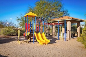 A playground with a slide, climbing structures, and a covered seating area.