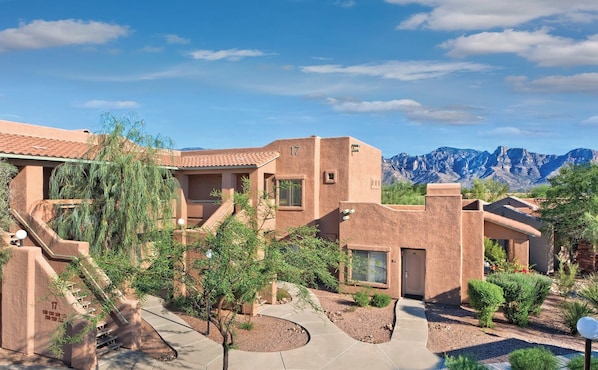 A modern building with a desert landscape and mountains in the background.