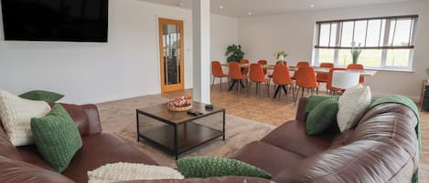 A modern living room with a brown leather sofa, a coffee table, and a TV mounted on the wall.