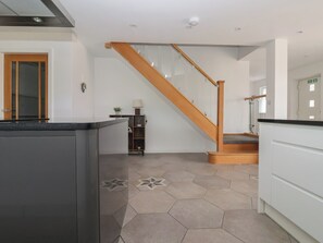 A modern kitchen with a wooden staircase, a countertop, and hexagonal patterned flooring. - Gravel Pit Cottage (Bridlington)