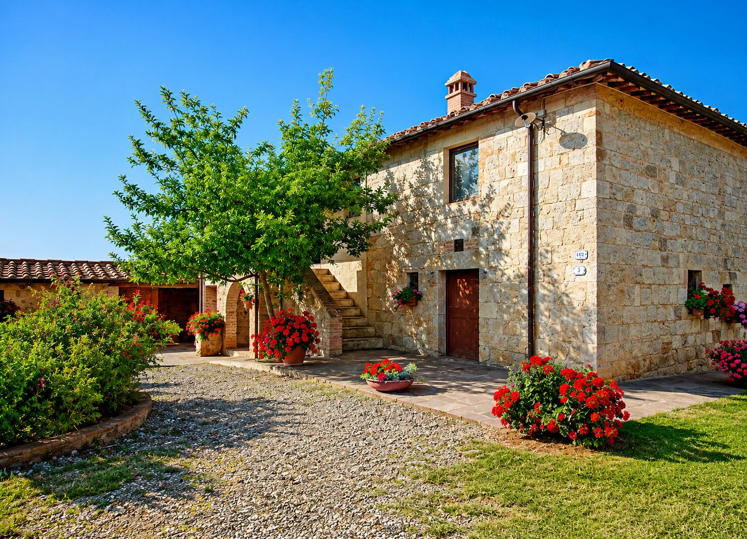 A stone building with a tiled roof, a staircase, and potted plants.