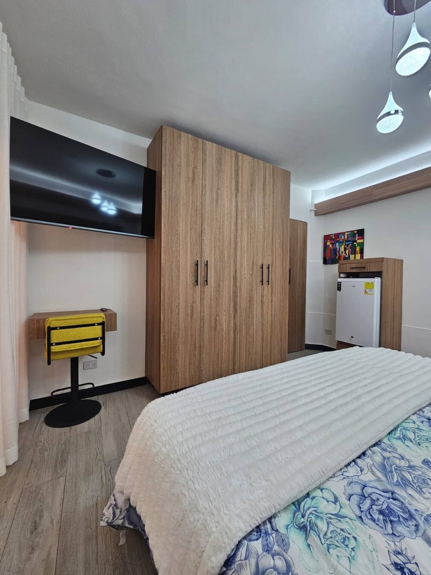 A bedroom with a bed, a wardrobe, a television, and a desk.