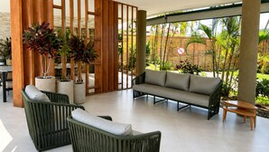 Un espace extérieur moderne, aménagé avec des meubles en osier, des plantes en pot et offrant une vue sur un jardin tropical.