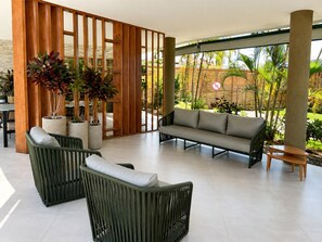 A modern outdoor seating area with wicker furniture, potted plants, and a view of a tropical garden. - Spacious 1-bedroom apartment with AC in perfect Ipojuca (Ipojuca)