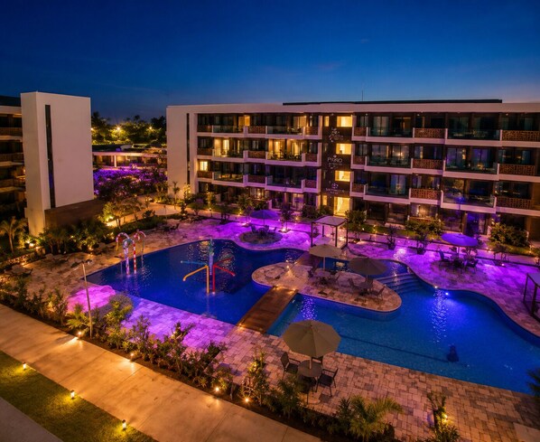 Et hotel med swimmingpool, flere balkoner og udendørs siddepladser.