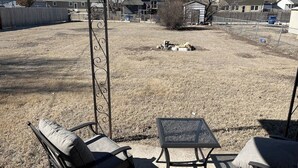 A backyard with a covered patio area, a metal fence, and a lawn. - -Cheerful 3 bed home--inside COMPLETELY renovated! (Hays)
