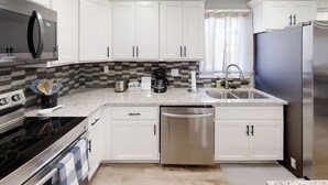 A modern kitchen with white cabinets, a stainless steel refrigerator, a microwave, and a dishwasher. - -Cheerful 3 bed home--inside COMPLETELY renovated! (Hays)