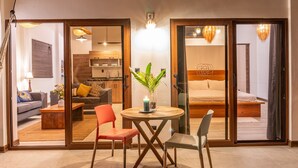 Une chambre d’hôtel moderne comprenant un coin repas, une cuisine et une chambre à coucher avec un lit et une table de chevet.