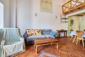 A living room with a sofa, a wooden coffee table, and a dining area with chairs and a table. - Casa Dos Irmaos in the Valley of the Orange Trees (Silves)
