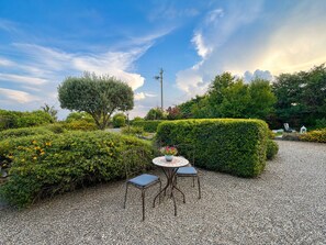 A garden with a gravel path, a table with chairs, and a variety of plants and trees. - Loft Sole – A Retreat with a Pool by Sicily Escape (Sicilia)