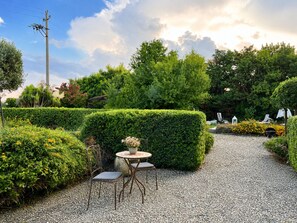 A garden pathway with a table and chairs, surrounded by neatly trimmed hedges and various plants. - Loft Sole – A Retreat with a Pool by Sicily Escape (Sicilia)