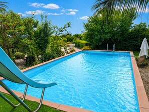 A rectangular swimming pool with clear blue water, surrounded by lush greenery and a clear sky. - Loft Sole – A Retreat with a Pool by Sicily Escape (Sicilia)