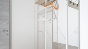 Guarda-roupa branco de metal com prateleira de madeira e espaço para pendurar.