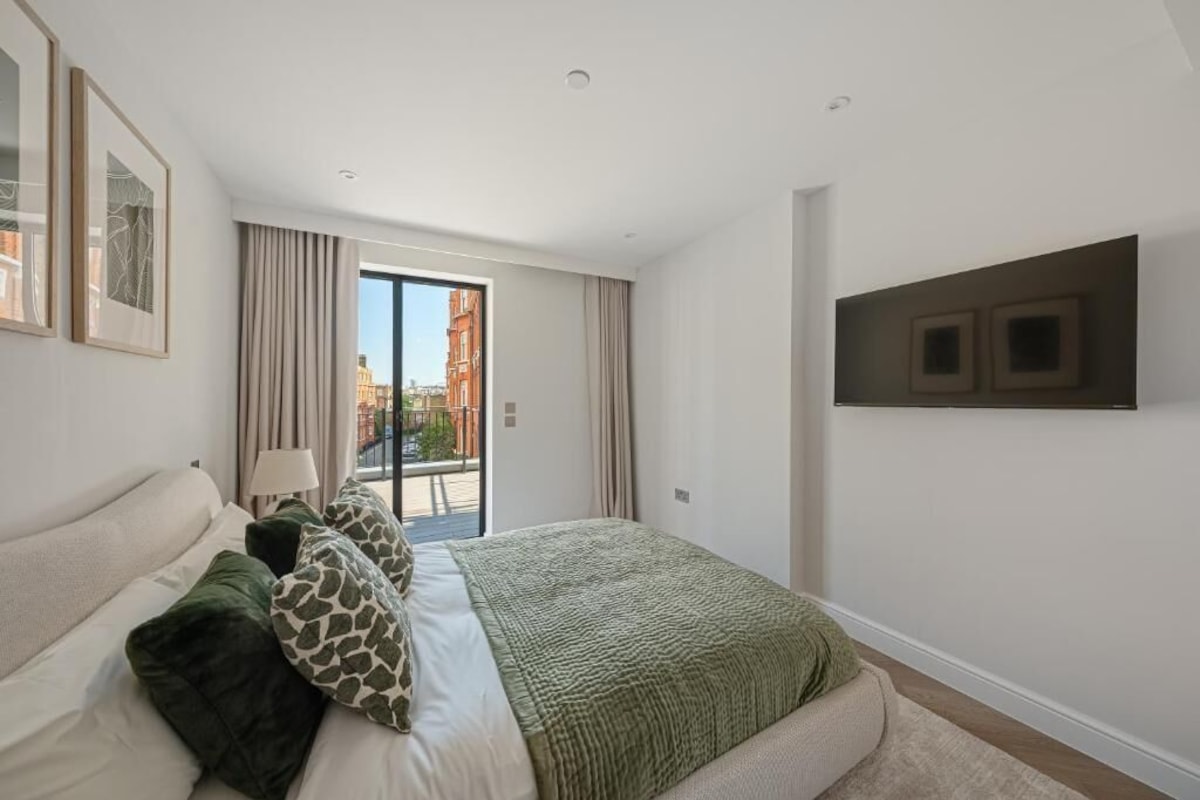 A modern bedroom with a large bed, a view to the outside, and a mounted TV on the wall.