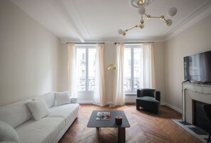Una sala de estar con sofá, mesa de centro, chimenea y televisor.