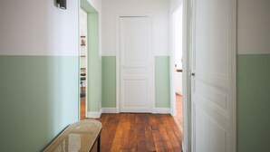 Un corridoio con pavimento in legno, una porta bianca e una panca.