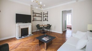Un soggiorno con camino, televisione, zona pranzo con sedie e divano.