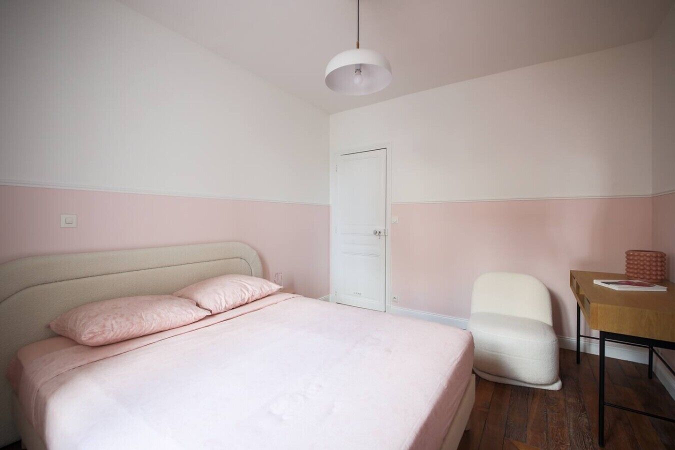 Ein Schlafzimmer mit Bett, Stuhl, Schreibtisch und einer Tür.