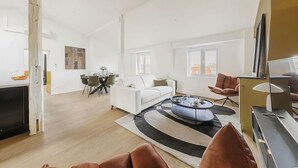 Ein modernes Wohnzimmer mit einem weißen Sofa, einem runden Couchtisch und einem Essbereich mit Tisch und Stühlen.